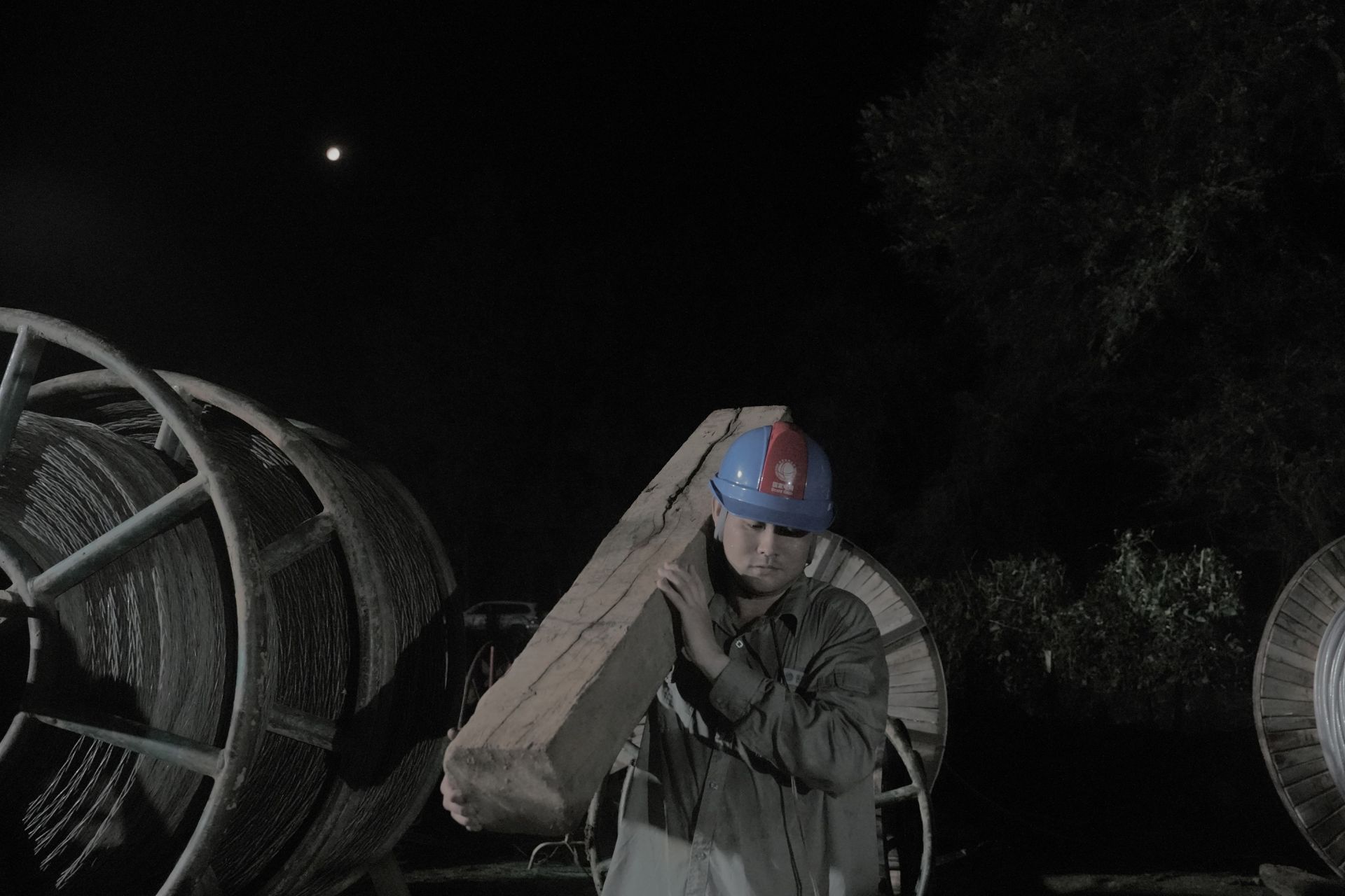 圖7：7月9日凌晨1時16分，湖北蒲圻電廠三期-赤壁500千伏線路工程跨越施工現場，國網湖北送變電公司員工姜夢迪  背運枕木。（